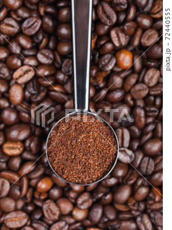 Fresh raw organic coffee powder in silver steel scoop on top of coffee beans. Fresh raw organic coffee powder in silver steel scoop on top of coffee beans. 72440555