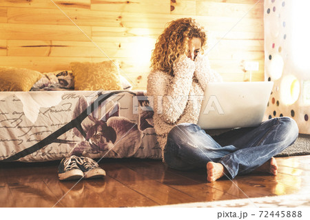 Surprised and scared caucasian woman looking a computer laptop monitor sit down on the wooden floor at home or hotel Surprised and scared caucasian woman looking a computer laptop monitor sit down on the wooden floor at home or hotel 72445888
