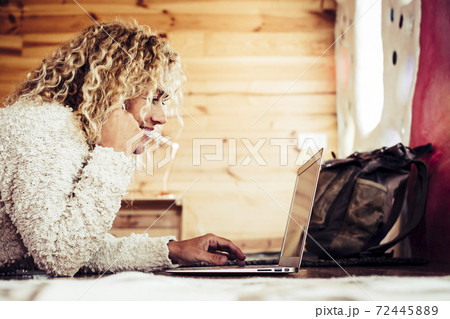 Beautiful happy caucasian adult woman work on a perconal laptop computer at home or hotel room - modern digitl nomad lifestyle and people free from office with technology 72445889