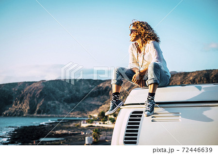 Travel concept with independent people enjoyig the outdoor leisure activity and wanderlust life lifestyle - woman sit down on the roof of a old nice vintage camper van 72446639