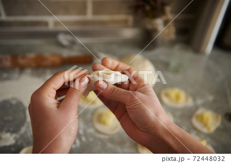A woman making traditional dumplings ( vareniki or ravioli ). Focus on hands A woman making traditional dumplings ( vareniki or ravioli ). Focus on hands 72448032