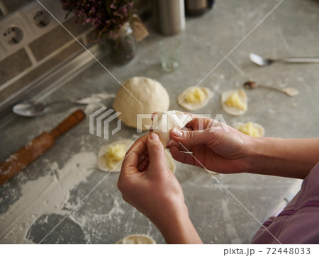 A young woman sculpts delicious dumplings in the kitchen. 72448033