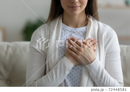 Close up wishful peaceful young woman holding hands on chest 72448581