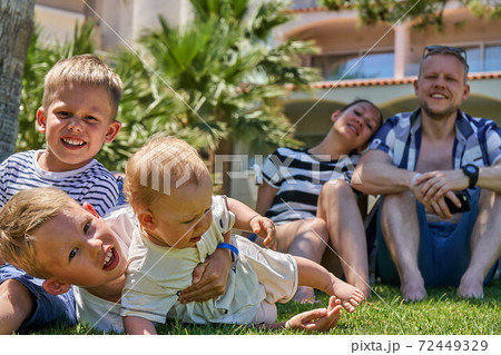 Happy family. Cheerful brothers playing on lawn near parents 72449329