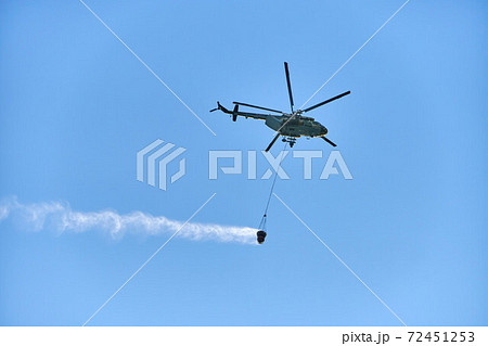 Fire fighting helicopter with water bucket on blue sky background 72451253