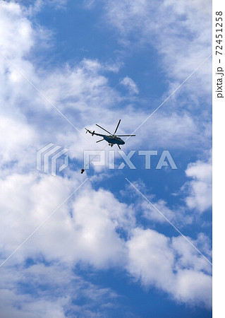 Fire fighting helicopter with water bucket on a cloudy sky background Fire fighting helicopter with water bucket on a cloudy sky background 72451258