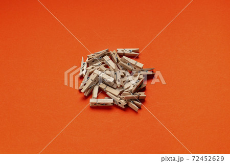 Many wooden clothespin on orange background. 72452629