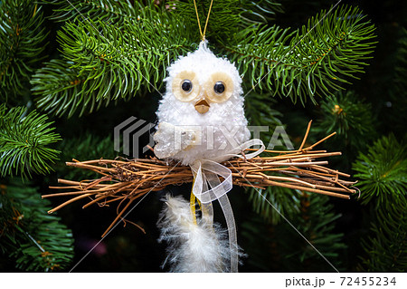 Russia. Saint-Petersburg. Christmas tree decoration a small white owl holds a bundle of firewood in its paws. Russia. Saint-Petersburg. Christmas tree decoration a small white owl holds a bundle of firewood in its paws. 72455234