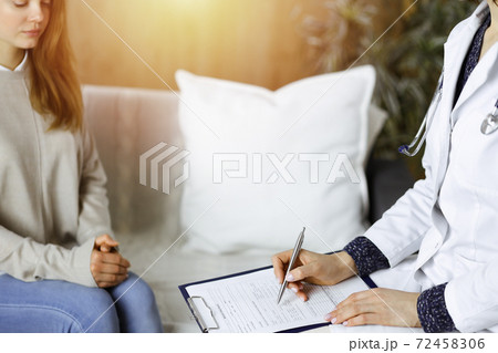 Close-up of woman-doctor and patient discussing current health examination while sitting indoors. Stay at home concept during Coronavirus pandemic and self isolation quarantine. Covid 2019 Close-up of woman-doctor and patient discussing current health examination while sitting indoors. Stay at home concept during Coronavirus pandemic and self isolation quarantine. Covid 2019 72458306