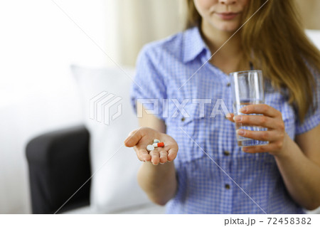 Close-up woman holding pills time to take medications, cure for headache, high blood pressure or cholesterol level remedy pain killer drugs. Medicine concept Close-up woman holding pills time to take medications, cure for headache, high blood pressure or cholesterol level remedy pain killer drugs. Medicine concept 72458382