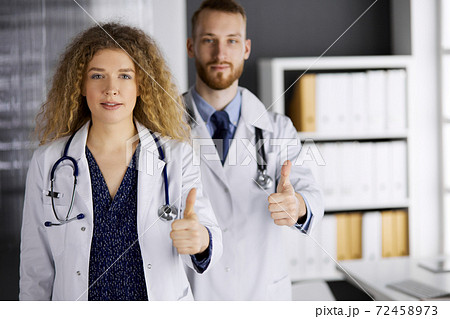 Two doctors standing with thumbs up in hospital office. Medical help, countering viral infection and medicine concept 72458973