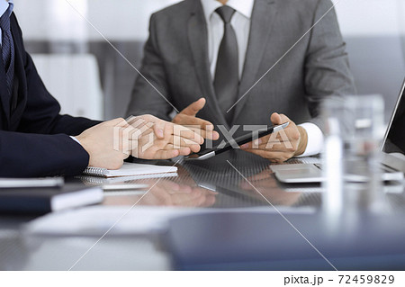 Unknown businessman using tablet computer and working together with his colleague while sits at the glass desk in modern office. Teamwork and partnership concept 72459829