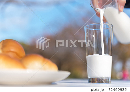 テラスのテーブルでピッチャーからグラスに牛乳を注ぐ朝食の風景 テラスのテーブルでピッチャーからグラスに牛乳を注ぐ朝食の風景 72460926