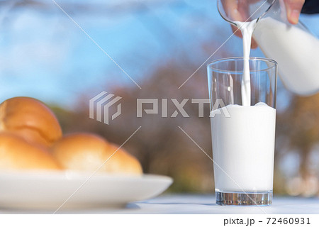テラスのテーブルでピッチャーからグラスに牛乳を注ぐ朝食の風景 72460931