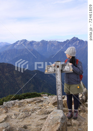 秋空の唐松岳に登頂した登山者と遠景の立山連峰（剱岳他） 72461809