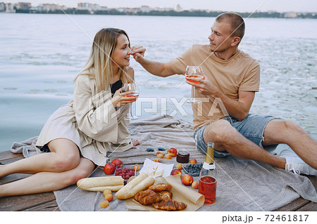 People sitting by the water with picnic set 72461817