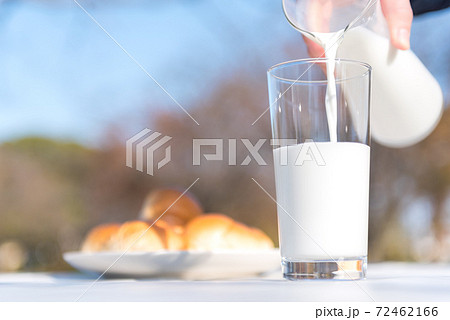 テラスのテーブルでピッチャーからグラスに牛乳を注ぐ朝食の風景 テラスのテーブルでピッチャーからグラスに牛乳を注ぐ朝食の風景 72462166