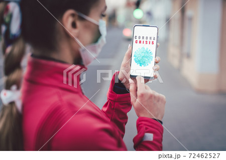 Woman using her phone to get news about the covid-19 crisis Woman using her phone to get news about the covid-19 crisis 72462527