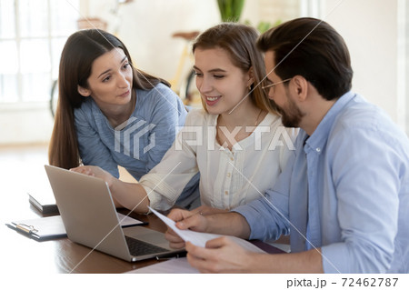 Smiling diverse colleagues cooperate on computer in office Smiling diverse colleagues cooperate on computer in office 72462787