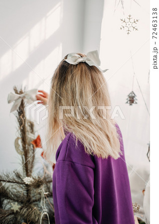 Holiday christmas decorating at home. Young woman putting ornaments on xmas tree, setting up lights. Budget hristmas Home Decor Ideas 72463138