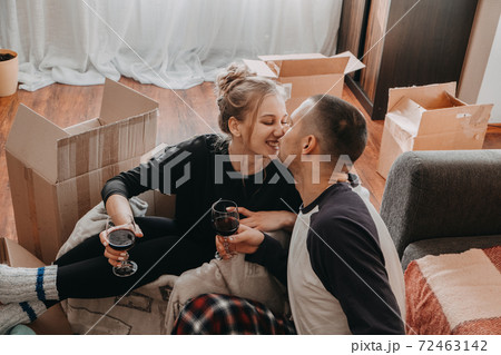 Moving Day, new home, Valentine's Day, unpacking boxes, newlyweds concept. Couple Celebrating Moving Into New Home and have fun With wine Moving Day, new home, Valentine's Day, unpacking boxes, newlyweds concept. Couple Celebrating Moving Into New Home and have fun With wine 72463142