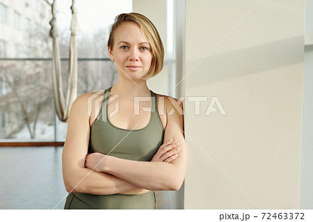Happy young fly yoga trainer in grey tracksuit keeping her arms crossed by chest Happy young fly yoga trainer in grey tracksuit keeping her arms crossed by chest 72463372
