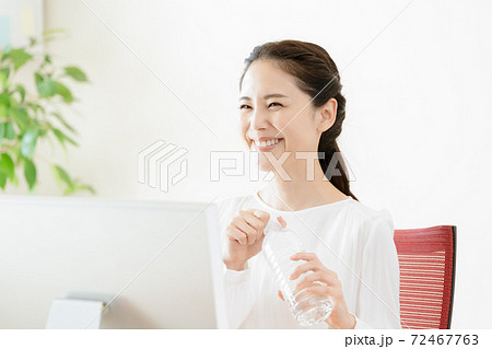 オフィスで水分補給する若い女性 72467763