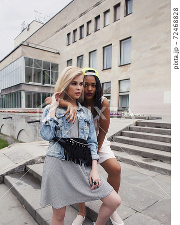 Two teenage diverse nations girls infront of university building smiling, having fun traveling europe, lifestyle people concept 72468828