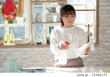 雑巾と消毒液のスプレーでキッチンの掃除をする若い女性 72469175