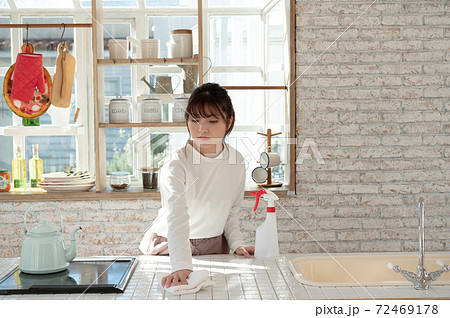 雑巾と消毒液のスプレーでキッチンの掃除をする若い女性 72469178