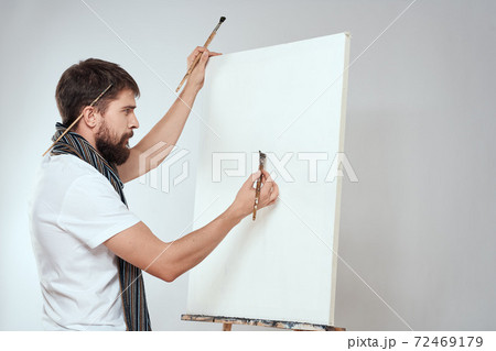Male artist brush in hands of easel art hobby light background scarf around his neck 72469179
