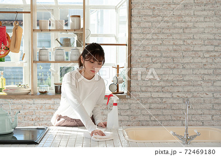 雑巾と消毒液のスプレーでキッチンの掃除をする若い女性 72469180