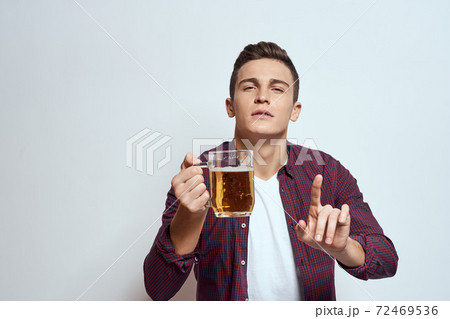 Drunk man with a mug of beer vacation alcohol lifestyle in a red shirt emotions light background Drunk man with a mug of beer vacation alcohol lifestyle in a red shirt emotions light background 72469536