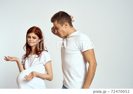 a pregnant woman and a young man are waiting for a baby on a light background emotions family love a pregnant woman and a young man are waiting for a baby on a light background emotions family love 72470052