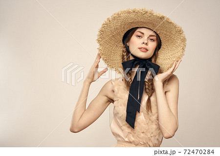 Romantic woman in a hat and dress on a light background gestures with her hands portrait fun emotions cropped view 72470284