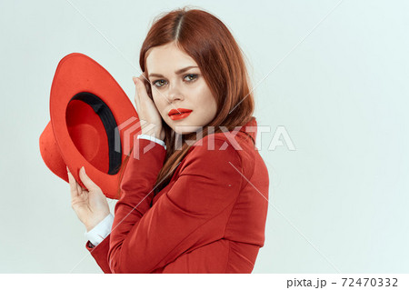 Elegant woman in red jacket hat holding long hair cropped light background 72470332