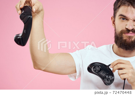 Man with two joysticks in hands fun game technology lifestyle pink background 72470448