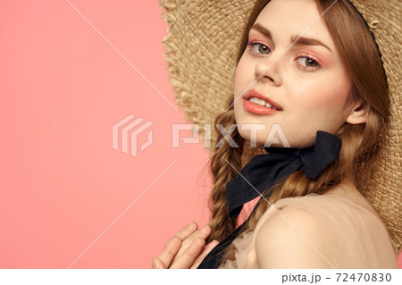 Portrait of a girl in a straw hat on a pink background emotions close-up beautiful face model pigtails 72470830