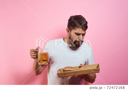 Man with tray of fast food and mug of beer french fries fast food cropped view 72472168