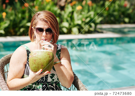 Woman enjoying coconut cocktail 72473680