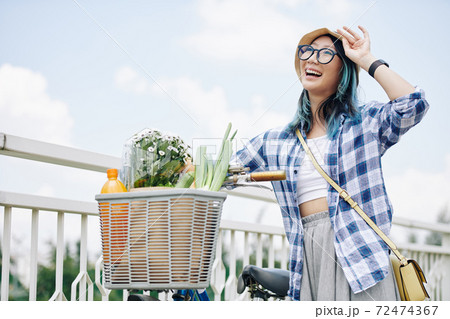 Happy woman standing next to bicycle 72474367