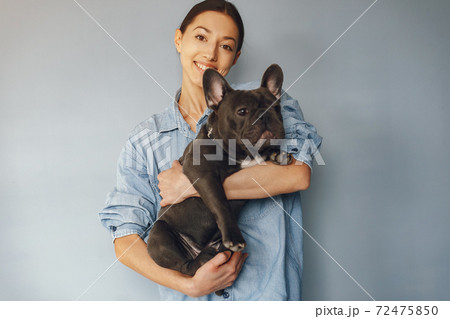 Elegant woman in a blue shirt with black bulldog Elegant woman in a blue shirt with black bulldog 72475850