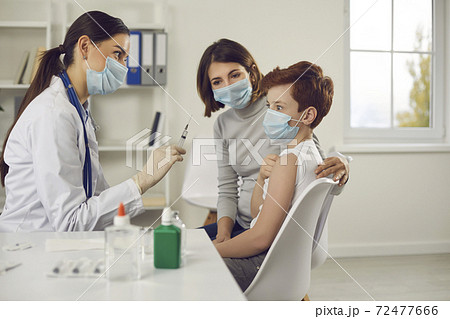 Scared little child makes funny face when he sees syringe needle in nurse's hand 72477666