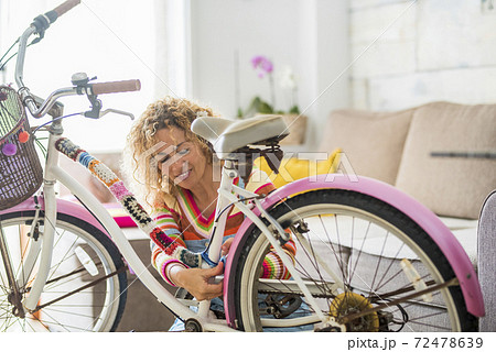 Beautiful caucasian young woman modifying a bike at home with handcrafted tailors art materials - people and colors with crazy art lifestyle - happiness working handmade 72478639