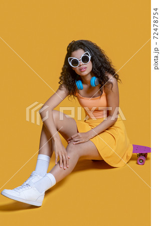 Pretty dark-haired young girl with a skateboard looking good Pretty dark-haired young girl with a skateboard looking good 72478754