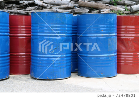 Empty tank of 200 liter fuel. blue and red color Put in front of old wood pile. 72478801