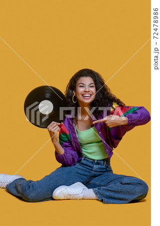 Sweet dark-haired young girl holding a vinyl record Sweet dark-haired young girl holding a vinyl record 72478986