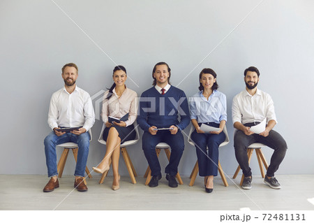 Smiling candidates job seekers sitting in row with resumes in hand and waiting for interview invitation turn Smiling candidates job seekers sitting in row with resumes in hand and waiting for interview invitation turn 72481131