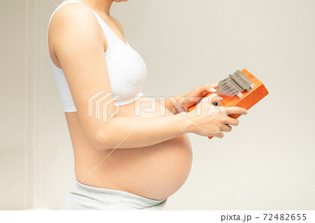A pregnant woman plays a kalimba instrument for her unborn child to listen. Music is something that will help your baby's brain development 72482655