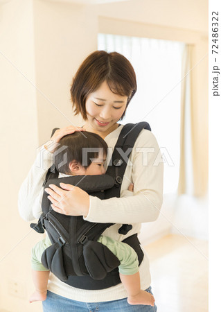 抱っこ紐で子供を寝かせる母親 72486322